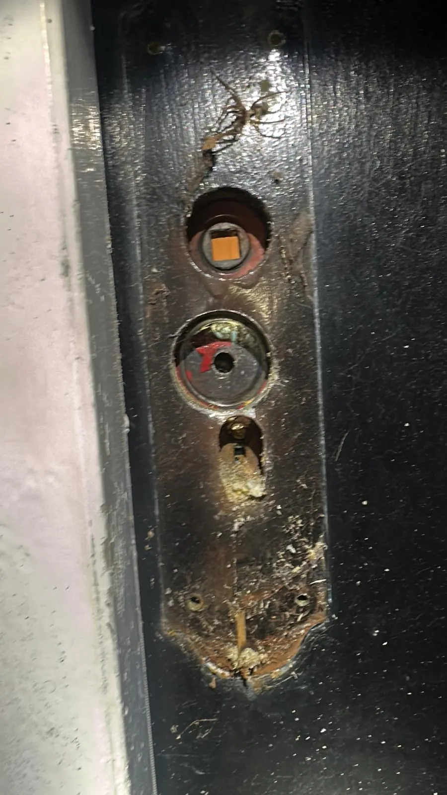 A worn fixing area around a lock on a dark door.