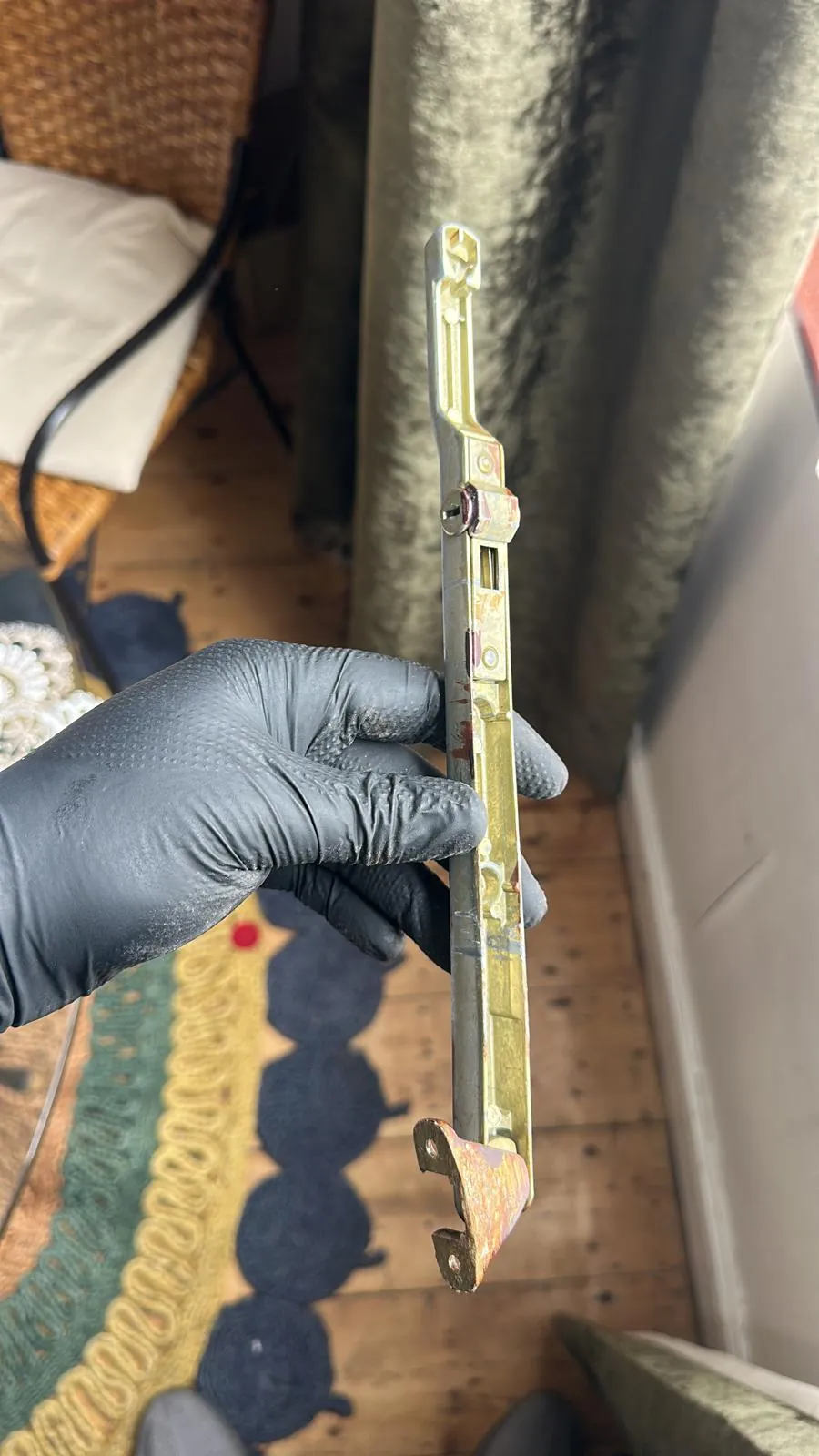 A long multipoint locking strip held in a gloved hand.